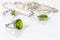 Closeup silver ring with peridot on background pendant and ring on white acrylic desk.