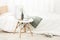 Closeup of a simple chair near a bed with a cup of coffee on it against a white wall