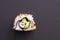 Closeup of a single piece of homemade not perfect sushi roll. Isolated on dark black background. Roll containing avocado, surimi,