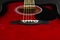 Closeup of a six stringed red acoustic guitar, from bridge side. Music entertainment background