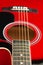 Closeup of a six stringed red acoustic guitar, from fingerboard side. Music entertainment background