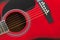 Closeup of a six stringed red acoustic guitar. Music entertainment background