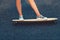 Closeup of skateboarder legs. Woman in sneakers riding skateboard outdoor.