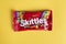 Closeup of Skittles candy made by Wm. Wrigley Jr. Company on yellow background