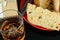 Closeup of a slice of panettone next to a knife, a glass with whiskey and ice and a gift box