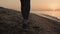 Closeup slim woman feet walking sandy beach at sunset. Girl steping on seacoast