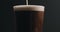Closeup slow motion pour dark stout beer in pint glass over black background