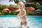 closeup small blonde girl smiles plays in shallow swimming pool