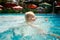 closeup small blonde girl swims smiles in hotel swimming pool