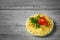 Closeup of a small load of bread spread with hummus, with a slice of tomato on a gray blurred background.