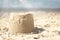 Closeup of a small sandcastle at the beach under the sunlight with a blurry background