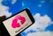 Closeup of smartphone with logo lettering of cloud computing provider service telekom magenta, blurred sky and cloud background