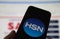 Closeup of smartphone screen with logo lettering of HSN home shopping network , blurred website background