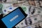 Closeup of smartphone screen with logo lettering of online money transfer service venmo, blurred banknotes background
