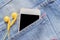 Closeup smartphone and Yellow earphone in denim jeans pocket.