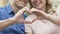 Closeup of smiling couple making heart symbol with hands outdoors, love