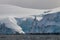 Closeup, snow and blue ice, Antarctic Peninsula. Small inlet in center. Clouds in background. Calm sea in foreground.