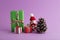 Closeup of a snowman, colorful gift boxes, and a pine cone in the purple background