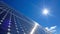 A closeup of a solar panel array glinting in the sunlight against a bright blue sky. The panels are carefully angled to