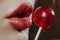 closeup of someones lips near a cherry red lollipop