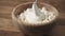 Closeup sour cream pour on cottage cheese in wood bowl