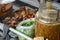 Closeup spicy sauce in the glass jar with blurred stewed pork and coriander in background