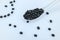 Closeup of a spoon of black soybeans, some scattered on light blue background
