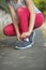 Closeup sporty girl tying shoelaces on sneakers outdoors.