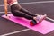 Closeup sporty woman training on mat outdoor summer day, massaging and stretching hamstring and ankle leg muscles