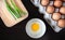 Closeup spring onion on wood butcher and fresh chicken egg in bowl and group of egg in box on wooden kitchen table for healthy and