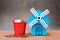 Closeup stack coins in red bucket with blue wind turbine using a