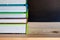 Closeup Stack of colorful books on wooden table with blackboard background. Time to learn and read concept
