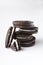 Closeup of stack of dark sandwich cookies and broken on the white background.Vertical image