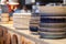 Closeup stack white and colored blue porcelain plates with oriental and ethnic ornament stands in open kitchen of trendy