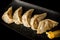 closeup steamed gyoza dumplings with sliced orange on plate