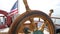 Closeup of a steering wheel and deck of a wooden antique Sail boat navigating in the ocean sunny day showing the wooden parts and