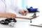 Closeup of stethoscope. Female doctor fills up medical form while sitting at the desk in hospital. Healthcare, workplace