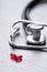 Closeup stethoscope near two red transparent capsules on gray table