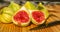 Closeup still life of group of whole panachee variegated striped figs on brown wooden cutting board with one fig sliced in half in