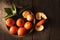 Closeup of still life of Minneola Tangelos on a plate with leaves and orange blossom on a rustic wood table, and warm side light