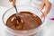 Closeup stirring mixing milk melted chocolate in glass bowl on white background