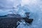 Closeup of a stranded iceberg in the shape of a frozen wave during midnight sun on a cloudy night at the black deamond beach in I