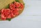 Closeup of a straw bonnet decorated with multiple silk roses on a white washed wooden background with copy space. Good for spring