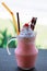 Closeup strawberry smoothies milkshake with whip cream and cherry for topping. Cold drink concept