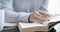 Closeup of a student hands writing notes from a textbook while studying. Person researching, listing information in a