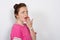 Closeup of a surprised red-haired woman with hands closing her mouth looking to the side isolated on a white background