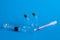 Closeup of syringe needles with the vaccine ampoules against a blue background - COVID-109