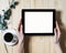 Closeup tablet with a empty blank screen monitor in the girls hands with a branch of eucalyptus and a cup of coffee on table back