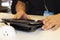 Closeup of tablet in leather case with stand on table with hands of worker helping a customer - blurred