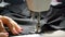 Closeup of tailor. Female hands of a seamstress at work. Sewing with a sewing machine with black material. Fashion